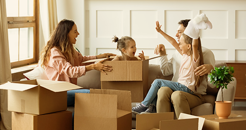 Family laughing with daughter popping out of moving box