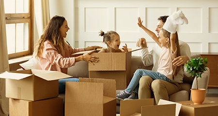 Family laughing with daughter popping out of moving box
