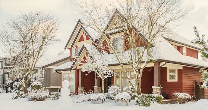 A red house surrounded by snow-covered ground, creating a picturesque winter scene.