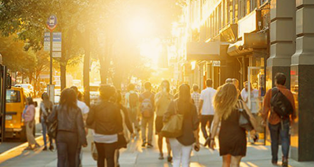 Busy city street with people walking and sun setting