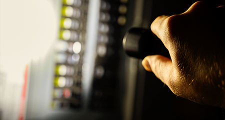 Person checking on electrical panel with flashlight