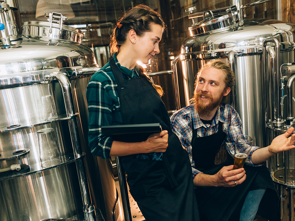 Two brewery workers looking at equipment