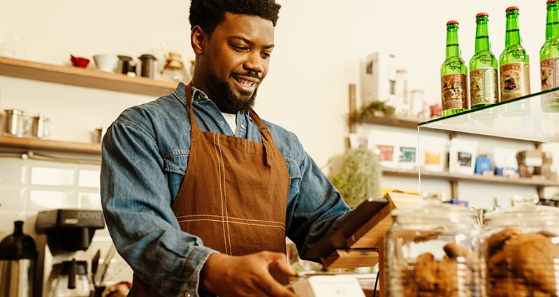 A man in an apron stands behind a counter, ready to assist customers with their needs.